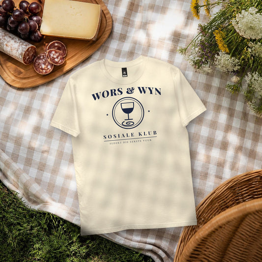 Wors & Wyn Sosiale Klub Tee in natural – flat lay on a picnic blanket with cheese, grapes and droë wors