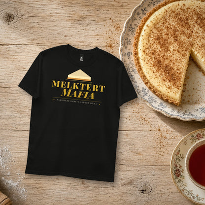 Melktert Mafia Tee in black – flat lay with a homemade melktert, rooibos tea and a rolling pin, gold 'Melktert Mafia' print